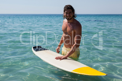 Surfer with surfboard standing in sea