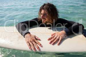 Surfer leaning on surfboard in sea