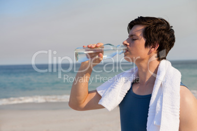 Man drinking water from bottle at beach