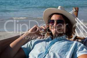 Man relaxing on hammock and talking on mobile phone on the beach