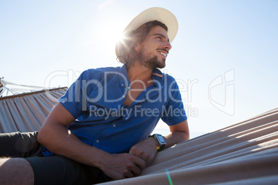 Smiling young man relaxing on hammock at beach