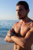 Thoughtful shirtless muscular man standing at beach