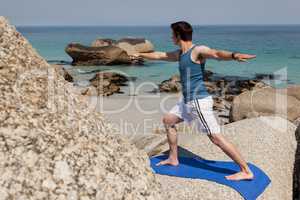 Man performing yoga on rock