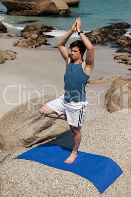 Man performing yoga on rock