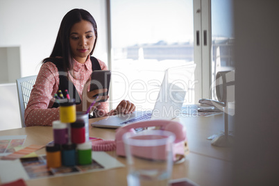 Young businesswoman using mobile phone at office desk