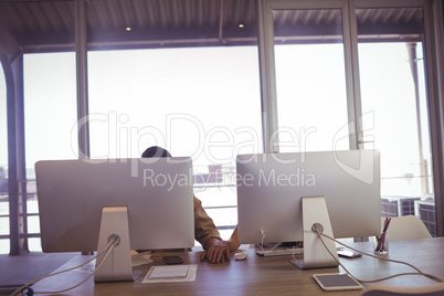 Businessman and businesswoman holding hands behind computers in office