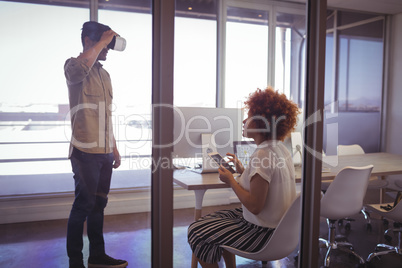 Businessman using VR glasses with businesswoman in office