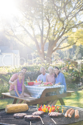 Close-up of barbecue and family sitting on the table