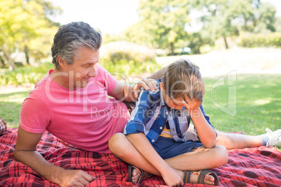 Father consoling his son at picnic in park