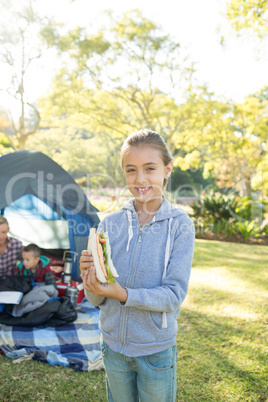 Smiling girl holding a sandwich at campsite