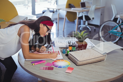 Businesswoman working while leaning on desk at office