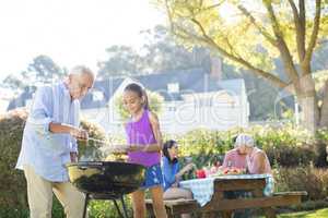 Grandfather and granddaughter preparing barbecue for their family
