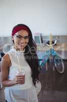 Portrait of happy businesswoman holding drink at office