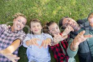 Happy family lying on the grass and making hand gestures