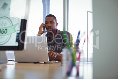 Businessman talking on phone while working in creative office