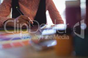 Mid section of businesswoman working on digitizer at office desk