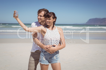 Happy couple taking selfie at beach
