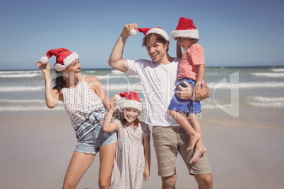 Smiling family wearing Santa hat at beach