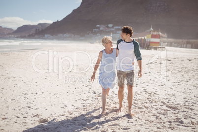 Young man with his mother walking on sand at beach