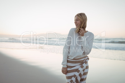 Thoughtful woman looking away while standing at beach