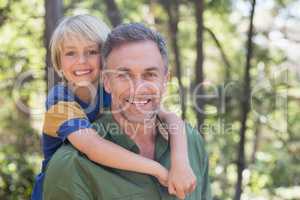 Smiling father piggybacking son in forest