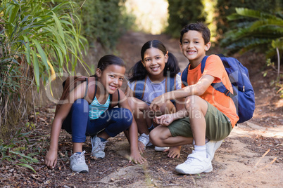 Smiling friends crouching on field at natural parkland