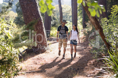 Happy couple hiking on trail in forest