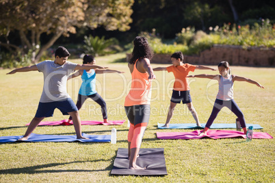 Instructor teaching kids Virabhadrasana II on mat