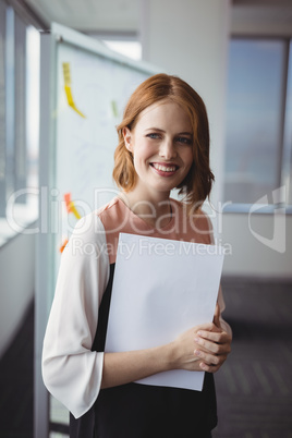 Portrait of smiling executive holding documents