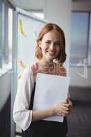 Portrait of smiling executive holding documents