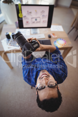 Overhead view of smiling executive holding digital camera at desk