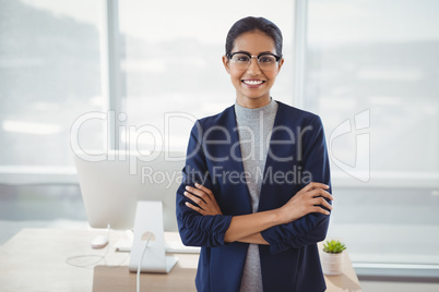Portrait of smiling executive standing with arms crossed