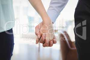 Mid section of couple standing with hand in hand