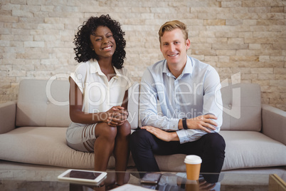 Portrait of smiling executives sitting on sofa