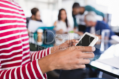 Midsection of businesswoman using phone while sitting with colleagues