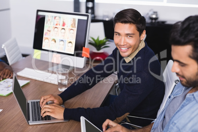 Portrait of happy businessman with colleague at desk