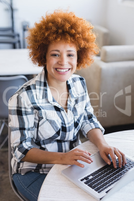 Portrait of smiling businesswoman using laptop at office