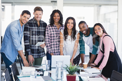 Portrait of smiling creative business team standing around desk