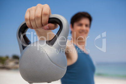 Low angle view of man holding kettlebell at beach