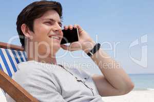 Smiling man talking on mobile phone at beach