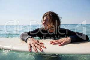 Surfer leaning on surfboard in sea