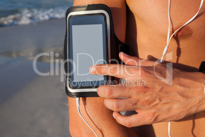 Muscular man using mobile phone on beach