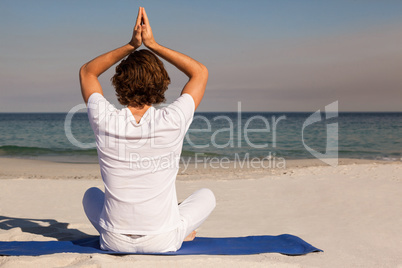 Man performing yoga at beach on sunny day