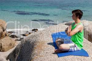 Man performing yoga on rock