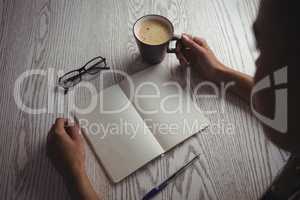 Businesswoman holding coffee cup on desk in office