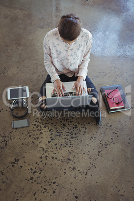 Creative businesswoman with laptop working on floor