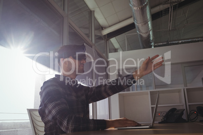 Young businessman gesturing while using virtual reality headset in office