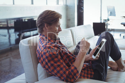 Smiling businessman holding mobile phone while resting in office