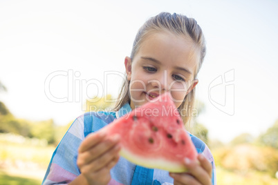 Smiling girl looking at watermelon slice in the park