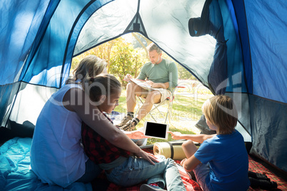 Kids and mother using tablet while father looking at the map
